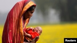 Monowara holds her 22-day-old grandson Arafat, as she walks through a mustard field on the outskirts of Dhaka, Bangladesh, Jan. 22, 2014.