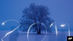 A man writing "2011" with a torch into the blue evening sky on a snow covered field in Sieversdorf, eastern Germany, 30 Dec 2010. (AFP Image)