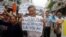FILE - Political dissident Nguyen Quang A (C) holds a sign which reads "Formasa - damaged the environment and is a criminal" during a protest in Hanoi, Vietnam, May 1, 2016.