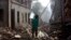 A Nepalese man carrying a water jar walks past damaged houses in Bhaktapur, Nepal, May 14, 2015. 