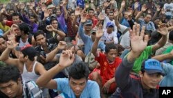 FILE - In this April 3, 2015 photo, rescued Burmese fishermen raise their hands as they are asked who among them wants to go home at the compound of Pusaka Benjina Resources fishing company in Benjina, Aru Islands, Indonesia. Two Indonesians and five Thai were arrested on charges of human trafficking connected with slavery in the seafood industry, Indonesian police said on May 12.