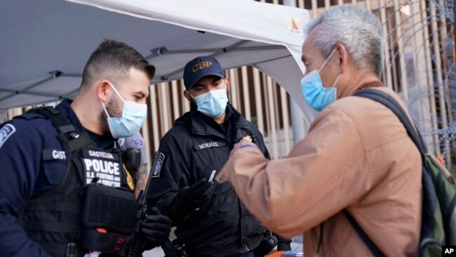 Oficiales de aduanas de Estados Unidos hablan con un hombre en el puerto de entrada de San Ysidro, el lunes 8 de noviembre de 2021, en Tijuana, México.