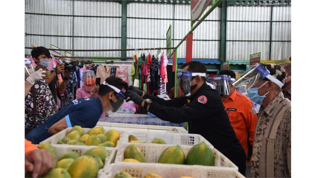 Sekdaprov Jawa Timur memakaikan pelindung wajah kepada para pedagang dan pengunjung Pasar Oro-oro Dowo Malang, Selasa, 21 Juli 2020. (Foto: Humas Pemprov Jawa Timur).