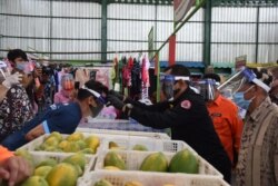 Sekdaprov Jawa Timur memakaikan pelindung wajah kepada para pedagang dan pengunjung Pasar Oro-oro Dowo Malang, Selasa, 21 Juli 2020. (Foto: Humas Pemprov Jawa Timur).