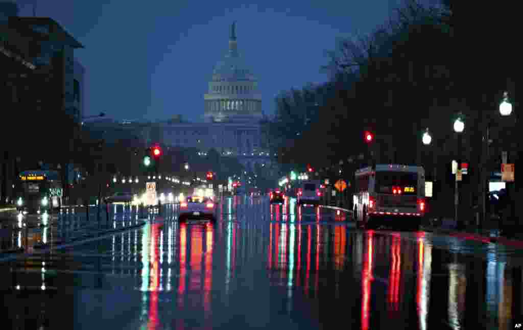 Gedung Capitol terlihat di latar belakang saat hujan turun di jalan Pennsylvania Avenue di Washington DC.