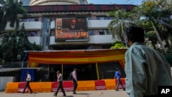FILE - A man watches a screen showing a news item featuring Russian President Vladimir Putin on the facade of the Bombay Stock Exchange (BSE) building in Mumbai, India, Thursday, Feb. 24, 2022. 