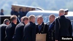 马航MH17班机遇难的荷兰人的灵柩7月23日抵达荷兰埃因霍恩机场。机场上举行了接机仪式。遇难者的灵柩正在被从抬下飞机，安放在灵柩车里。