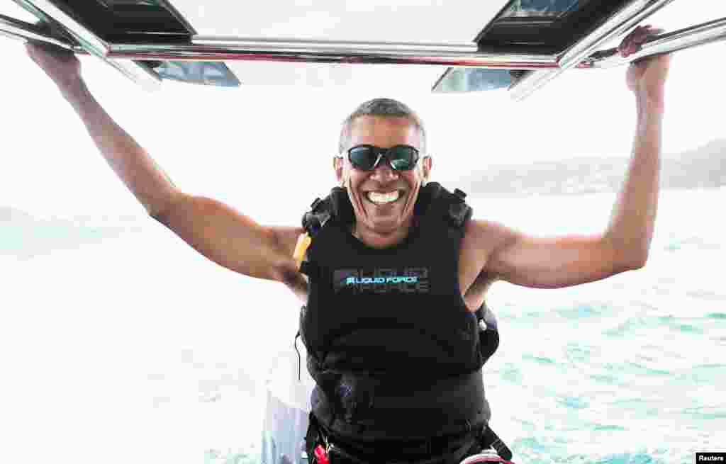 Former U.S. President Barack Obama sits on a boat during a kite surfing with British businessman Richard Branson during a vacation on Branson&#39;s Moskito island, in the British Virgin Islands, in a picture handed out by Virgin.