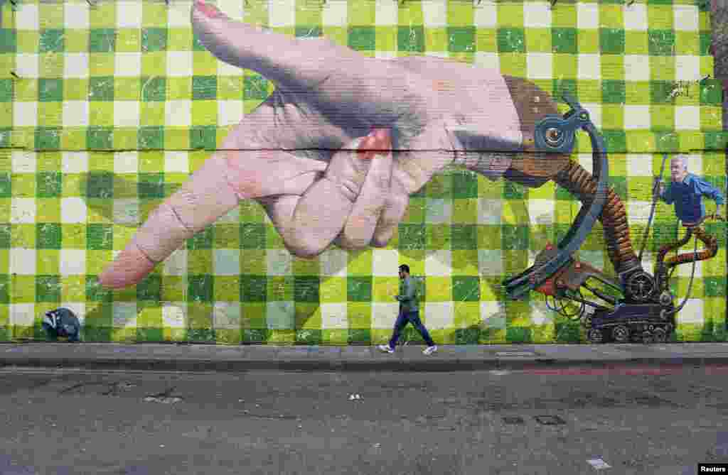 A man walks past a piece of street art in Shoreditch, London.