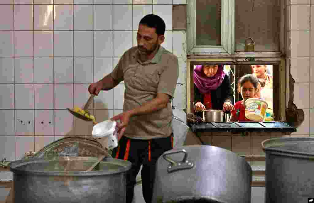 در مسجدی در بغداد، خانواده های آوارگان برای افطار غذای رایگان دریافت می کنند. 