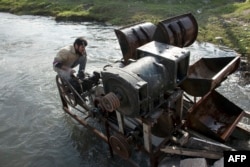 A Syrian man installs a homemade hydroelectric generator, assembled by 43-year-old Abu Saleh, in the Queiq river in the rebel held Bustan al-Qasr district in the east of the northern Syrian city of Aleppo, Nov. 26, 2015.