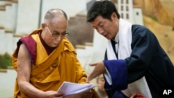 Lobsang Sangay, prime minister of the Tibetan government-in-exile, right, presents a document to spiritual leader the Dalai Lama at the Tibetan Children’s Village School in Dharmsala, India, June 5, 2014.