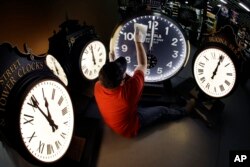 In this Thursday, Nov. 3, 2016 photo, Dan LaMoore wipes down a Shinola clock at Electric Time Co., in Medfield, Mass.