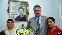 European Union representative Adrianus Koetsenruijter (C) poses with Manoubia Bouazizi (L), mother of Mohamed Bouazizi, a 26-year-old who set himself alight on Dec. 17, 2010 - he is seen on a poster behind - and Leila, sister of Mohamed, outside Tunis, No