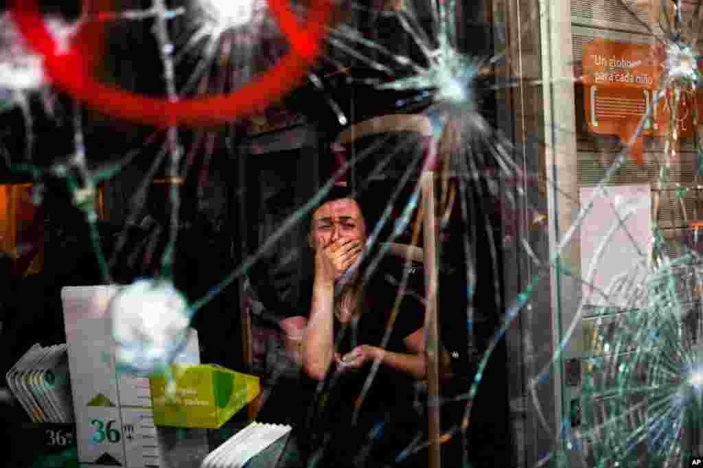 March 29: Mireia Arnau sits behind the broken glass of her shop which was stormed by demonstrators during a general strike in Barcelona to protest Spanish labor reforms.