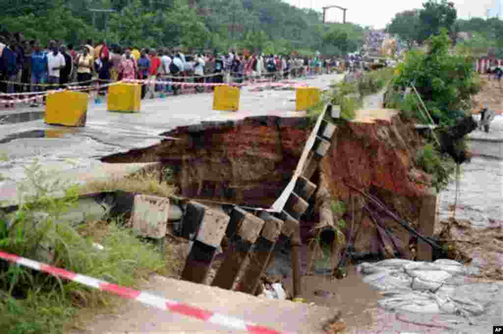 Tanzanians walk next to collapsed Kawe Bridge, Thursday Dec. 22, 2011. The bridge that connects the old town of Bagamoyo and Dar es Salaam's city centre collapsed on Wednesday night following fresh flooding. Government officials put the death toll to 25 a