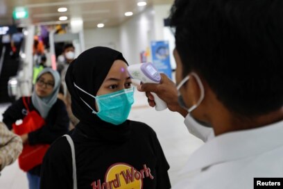 Seorang tenaga kesehatan memeriksa suhu penumpang Moda Raya Terpadu (MRT) di sebuah stasiun, Jakarta, 5 Maret 2020. (Foto: Reuters)