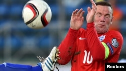 Wayne Rooney (à droite) tente de se couvrir après une parade lors du match de qualification de l’Euro 2016 (football) contre Saint-Marin au stade olympique de Serravalle, Saint-Marin, 5 Septembre2015.