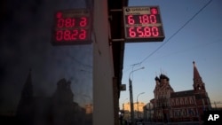 FILE - An exchange office screen reflects on a wall as it shows the currency exchange rate of the Russian ruble and U.S. dollar, with the Church of St. Nicholas on Bolvanovka in the background, in Moscow, Russia, April 11, 2018.