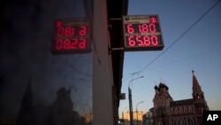 An exchange office screen reflects on a wall as it shows the currency exchange rate of the Russian ruble and U.S. dollar, with the Church of St. Nicholas on Bolvanovka in the background, in Moscow, Russia, April 11, 2018.