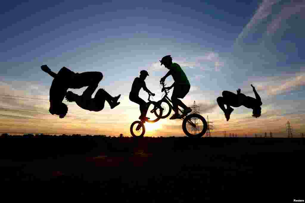 Youths wearing protective face masks use bicycles and perform a somersault as they practice parkour, during the holy month of Ramadan in the holy city of Najaf, Iraq, May 3, 2020.