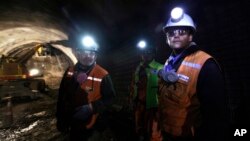 FILE - Foreman Jorge Villanueva, left, and supervisor Omar Rosales, right, look toward the entrance of a tunnel drilled under the Chuquicamata copper mine in the Atacama desert in northern Chile, Sept. 25, 2012.
