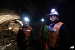 FILE - Foreman Jorge Villanueva, left, and supervisor Omar Rosales, right, look toward the entrance of a tunnel drilled under the Chuquicamata copper mine in the Atacama desert in northern Chile, Sept. 25, 2012.