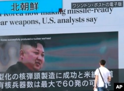 A man walks by a TV news program showing an image of North Korean leader Kim Jong Un while reporting North Korea's rocket launch, in Tokyo, Aug. 9, 2017.