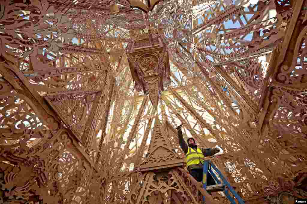 A lighting technician puts the finishing touches to Temple, a cross-community arts project that aims to demonstrate the transformative power of the arts in Londonderry. Northern Ireland. It has been built and raised by more than 100 individuals drawn from communities across the city, working together with Californian artist David Best. It will be burned to the ground in a special ceremony March 21.