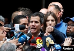 Venezuelan opposition leader and self-proclaimed interim president Juan Guaido, accompanied by his wife Fabiana Rosales, speaks to the media after a church service in Caracas, Venezuela, Jan. 27, 2019.