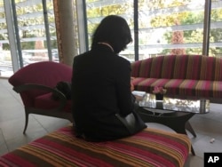 FILE - Grace Meng, the wife of missing Interpol President Meng Hongwei, who does not want her face shown, consults her mobile phone in the lobby of a hotel in Lyon, central France, where the police agency is based, Oct. 7, 2018.