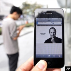 Un homme tenant un iPhone 4 montrant l'avis nécrologique de Jobs