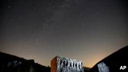 Stars and meteor streaks, near the line of horizon, are seen behind a medieval tombstone believed to be built in the 12th century depicting an ancient ritual dance, near the village of Umoljani, 50 kilometers (31 miles) southeast of Sarajevo, Bosnia, Aug. 11, 2017. The annual Perseid meteor shower reached its peak Saturday night.