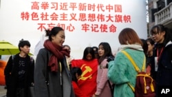一群大学生手举中共党旗在写有“习近平语录”的宣传板前合影。（2017年11月19日）