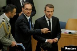 French President Emmanuel Macron, right, arrives for a high-level meeting to discuss the current situation in Libya during the 72nd U.N. General Assembly at U.N. headquarters in New York, Sept. 20, 2017.