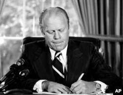 FILE - President Gerald Ford signs a document granting former President Richard M. Nixon "a full, free and absolute pardon" for all "offenses against the United States" during the period of his presidency. Ford signed the document, Sept. 8, 1974.