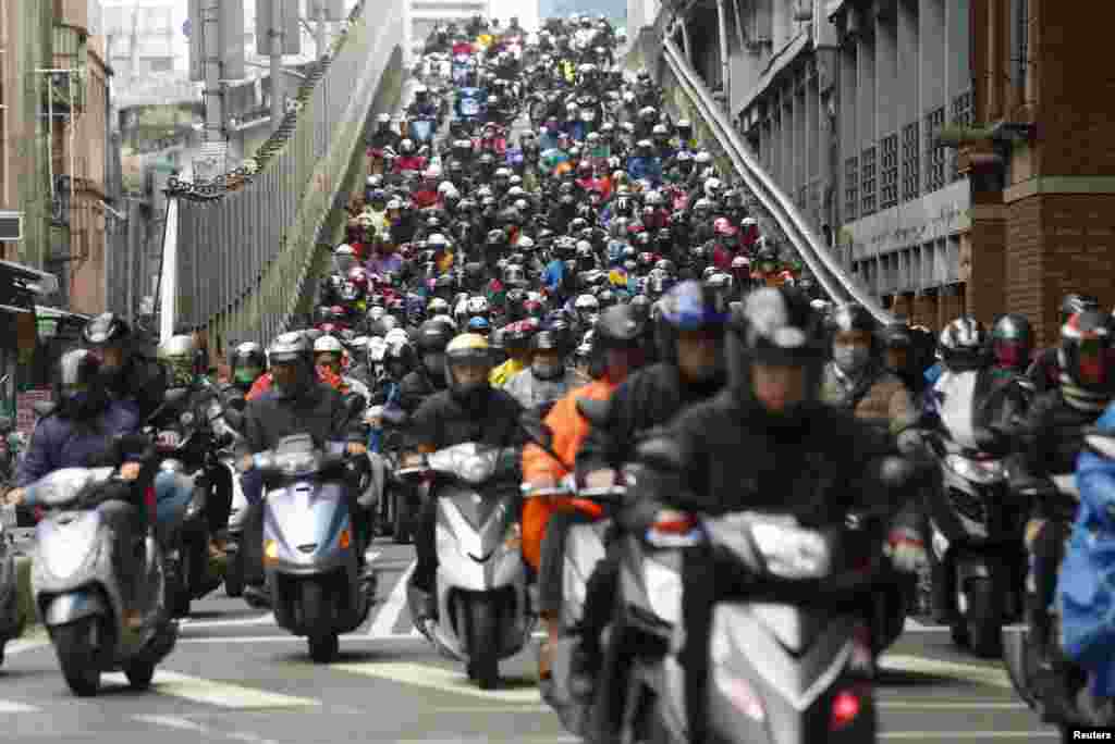 Pengendara sepeda motor berangkat kerja melewati sebuah jembatan pada jam sibuk pagi hari di Taipei, Taiwan.