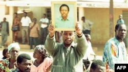 Un proche brandit la photo du journaliste Norbert Zongo lors de ses funérailles à Ouagadougou, Burkina, 16 décembre 1998.