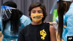 In this Monday, May. 24, 2021, photo high school student Alex Bugarin, 13, is vaccinated at a school-based COVID-19 vaccination clinic for students 12 and older at the LAUSD San Pedro High School John M. and Muriel Olguin Campus in San Pedro, Calif. (AP P