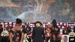 U.S. Secretary of State Hillary Clinton, center, pays her respects after signing the guest book for Ghana's late President John Atta Mill's funeral in Accra, Ghana, August 10, 2012.