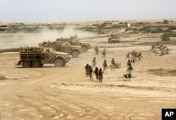 FILE - Iraqi, U.S. and Spanish soldiers participate in a training mission outside Baghdad, Iraq, May 27, 2015.