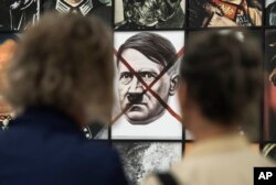 FILE - Visitors stand in front of the work 'Real Nazi' by Polish artist Piotr Uklanski during the press preview of the documenta 14, the world's most significant exhibition of contemporary art, in Kassel, Germany, June 8, 2017.