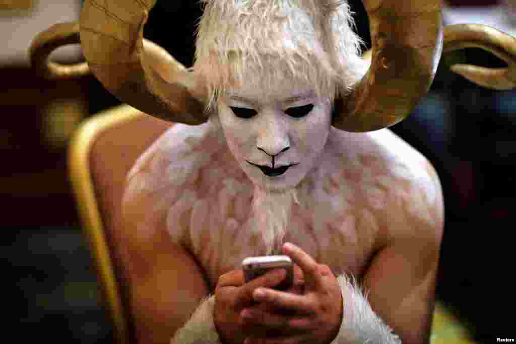 A performer in a ram costume looks at his phone backstage during a performance in Kunming, Yunnan province, Dec. 30, 2014.