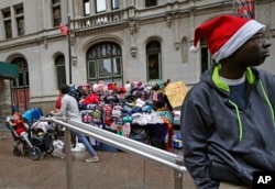 FILE - A New York street vendor waits for customers to buy his winter hats and sweatshirts on Christmas Eve in lower Manhattan's Zuccotti Park, Dec. 24, 2015.