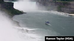 A ‘Maid of the Mist’ vessel sails past the American and Bridal Veil Falls, toward Horseshoe Falls, where poncho-suited tourists are often soaked by a thick mist. (R. Taylor/VOA)