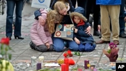 A woman and children sit and mourn for the victims of the bombings at the Place de la Bourse in the center of Brussels, Wednesday, March 23, 2016. (AP Photo/Martin Meissner)