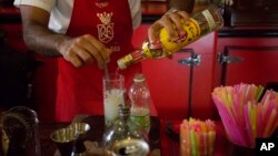 FILE - A bartender pours Cuban Havana Club rum as he prepares a mojito at the Floridita bar in Havana, June 8, 2016. Two liquor giants are escalating a 20-year fight to secure the rights to sell Havana Club rum in the United States when the Cuban embargo finally ends.