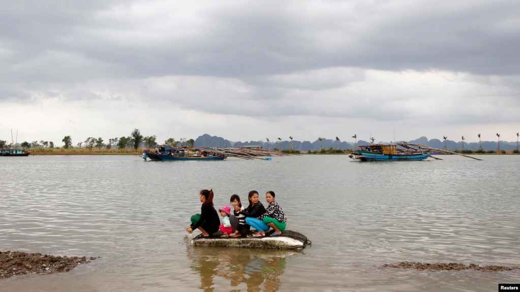Phụ nữ và trẻ em sơ tán trên chiếc thuyền con sau khi bão Haiyan ập vào tỉnh Quảng Ninh, cách Hà Nội 180 km ngày 11/11/2013. 13 người thiệt mạng. REUTERS/Kham 