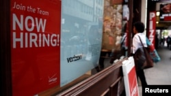 FILE - A "Now Hiring" sign is posted on a Verizon store in Manhattan in New York City, May 10, 2016.