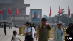 Visitors walk near a portrait of Sun Yat-sen, the first provisional president of the Republic of China, in Beijing's Tiananmen Square on Labour Day, May 1, 2020.